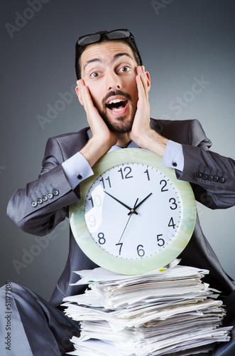 Photo: Man with clock and pile of papers Man with clock and pile of papers