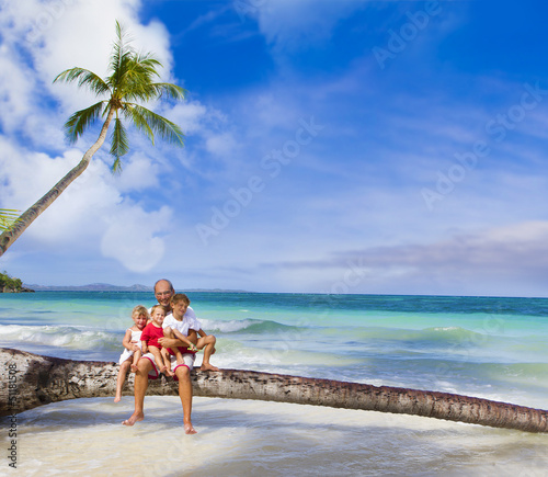 Photo: happy smiling family father and three kids on tropical beach and happy smiling family father and three kids on tropical beach and