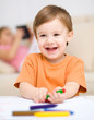 Little boy is drawing on white paper
