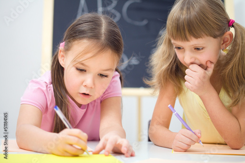 Photo: Little girls are writing using a pen Little girls are writing using a pen