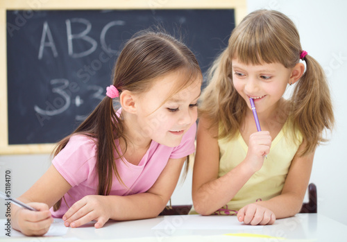 Photo: Little girls are writing using a pen Little girls are writing using a pen