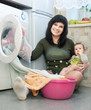  woman with baby putting clothes in to washing machine