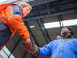 European deck officer friendly shakes a hand of African motorman