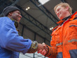 European deck officer friendly shakes a hand of African motorman