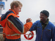 European deck officer friendly shakes a hand of African motorman