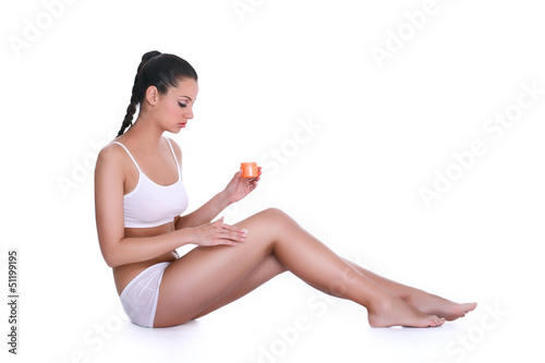 Photo: Young woman applying lotion on her body Young woman applying lotion on her body