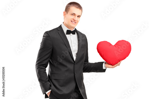 Photo: A young man wearing black suit and holding a red heart A young man wearing black suit and holding a red heart