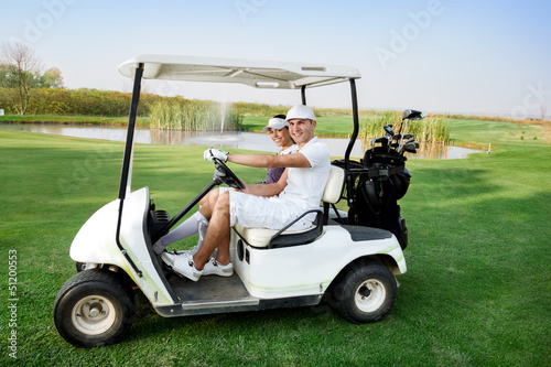 Photo: Couple in buggy in golf course Couple in buggy in golf course