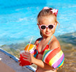 Child drinking  near swimming pool.