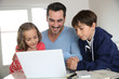 Man with children using laptop at home