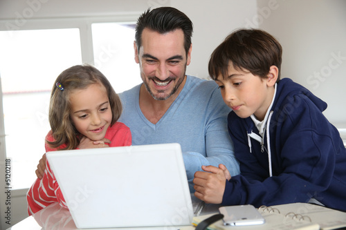Photo: Man with children using laptop at home Man with children using laptop at home