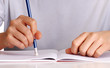 Manos borrando, escribiendo en un cuaderno.