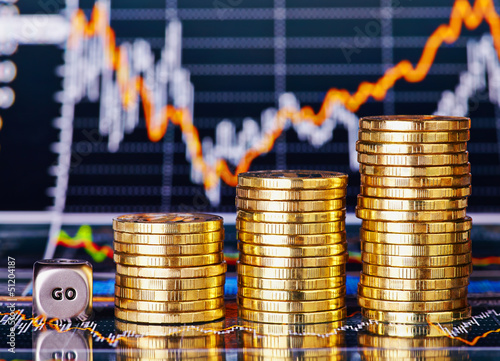 Photo: Uptrend stacks coins, dices cube with the word GO on the financi Uptrend stacks coins, dices cube with the word GO on the financi