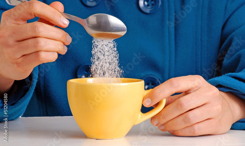 Photo: Colocando azúcar en una taza de café,cucharada de azúcar. Colocando azúcar en una taza de café,cucharada de azúcar.