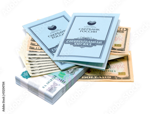 Photo: Two savings books lie on a stack of money on white background Two savings books lie on a stack of money on white background
