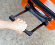 Woman holds orange suitcase in hand