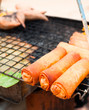 Foto: Traditional Thai food at market. Spring rolls on grill Traditional Thai food at market. Spring rolls on grill