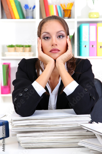 Photo: Sad business woman with documents in her workplace Sad business woman with documents in her workplace