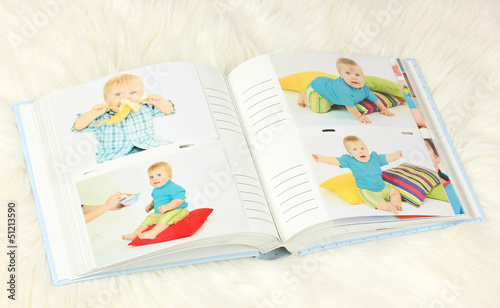 Photo: Open photo album with pictures on white carpet Open photo album with pictures on white carpet