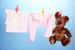 Baby clothes hanging on clothesline, on color background