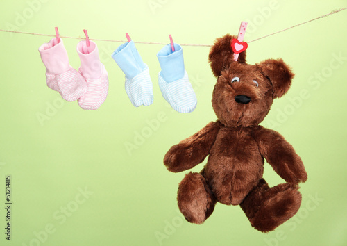 Photo: Baby booties hanging on clothesline, on color background Baby booties hanging on clothesline, on color background