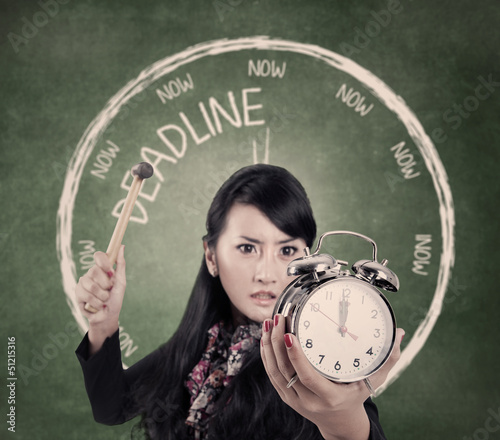 Photo: Angry businesswoman ready to hit an alarm clock Angry businesswoman ready to hit an alarm clock