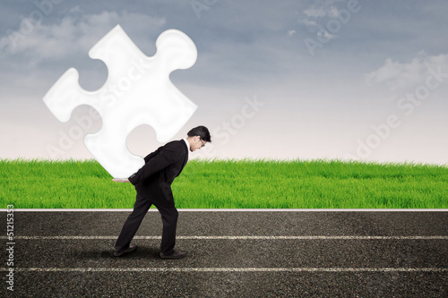 Photo: Asian businessman carry puzzle on the road Asian businessman carry puzzle on the road