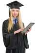 Young woman in graduation gown using tablet pc