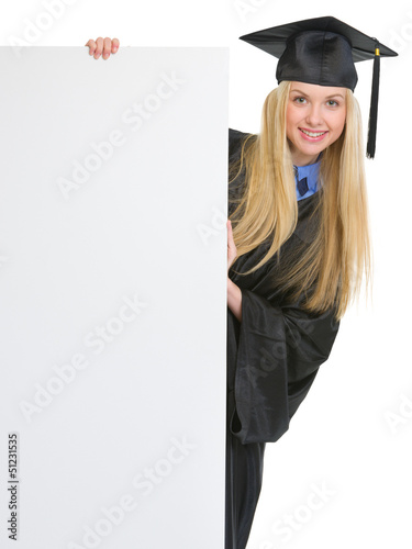 Photo: Woman in graduation gown looking out from blank billboard Woman in graduation gown looking out from blank billboard