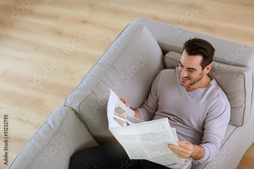 Photo: Upper view of man reading newspaper in sofa Upper view of man reading newspaper in sofa