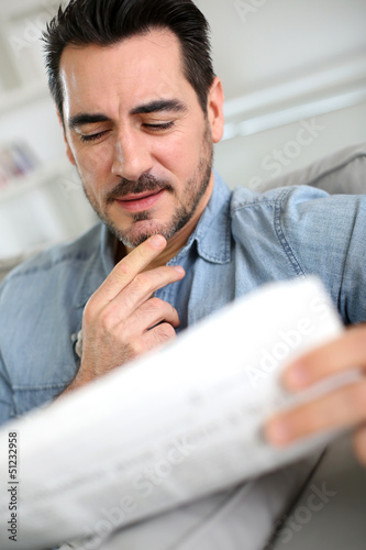 Photo: Man reading newspaper with attentive look Man reading newspaper with attentive look