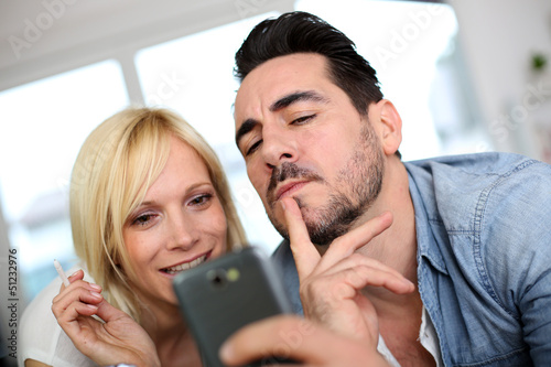 Photo: Cheerful couple having fun using smartphone Cheerful couple having fun using smartphone