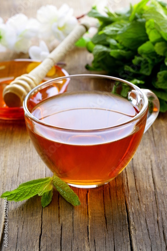 Photo: cup of tea with mint and honey on a wooden table cup of tea with mint and honey on a wooden table