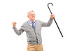 Happy senior man holding a cane and gesturing happiness