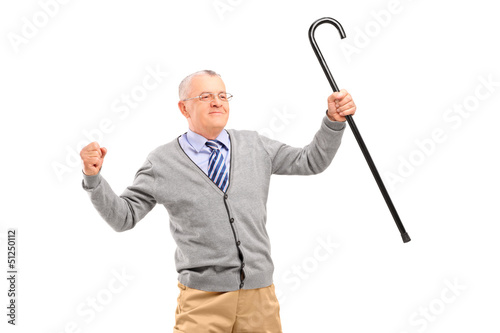 Photo: Happy senior man holding a cane and gesturing happiness Happy senior man holding a cane and gesturing happiness