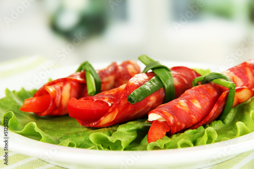 Photo: Salami rolls on white plate on bright background Salami rolls on white plate on bright background