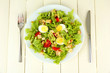 Caesar salad on white plate, on color wooden background