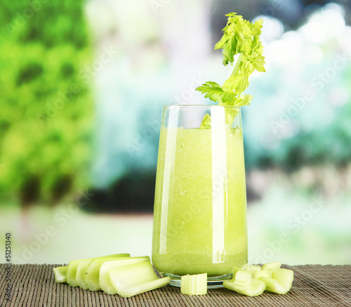 Photo: Glass of celery juice, on bamboo mat, on green background Glass of celery juice, on bamboo mat, on green background