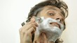 shaving with safety razor and shaving cream over white