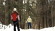 girls (persons) goes on skis on the snow road in the wood