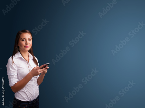 Photo: Young woman standing and typing on her phone with copy space Young woman standing and typing on her phone with copy space