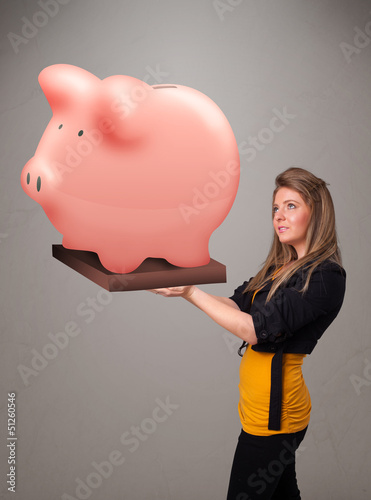 Photo: Young girl holding a huge savings piggy bank Young girl holding a huge savings piggy bank
