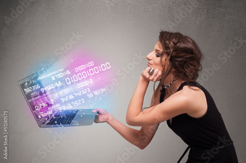 Photo: Casual woman holding laptop with exploding data and numers Casual woman holding laptop with exploding data and numers
