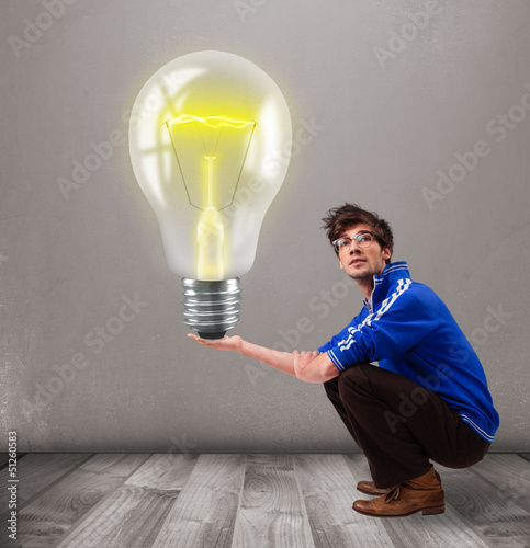 Photo: Attractive man holding realistic 3d light bulb Attractive man holding realistic 3d light bulb