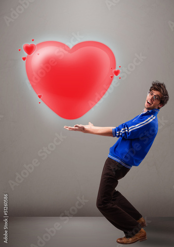 Photo: Young man holding lovely 3d red heart Young man holding lovely 3d red heart