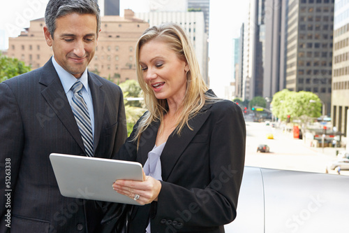 Photo: Businessman And Businesswoman Using Digital Tablet Outside Businessman And Businesswoman Using Digital Tablet Outside