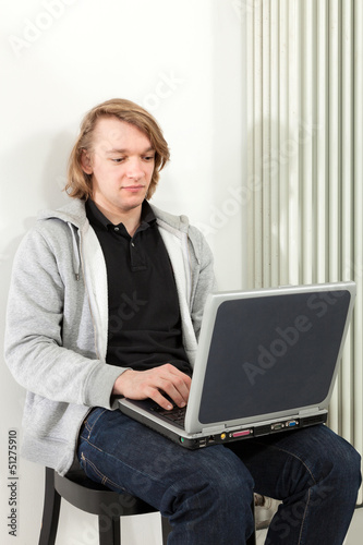 Photo: guy sitting with laptop near the radiator, guy sitting with laptop near the radiator,