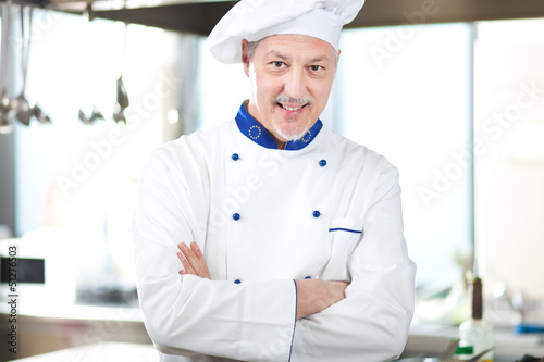 Photo: male chef smiling while standing in restaurant kitchen male chef smiling while standing in restaurant kitchen
