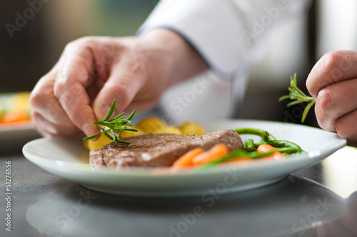 Photo: Chef hands decorating a dish in restaurant kitchen Chef hands decorating a dish in restaurant kitchen
