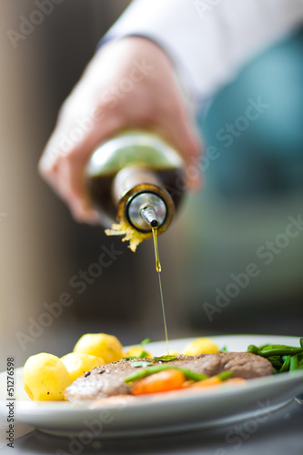 Photo: Chef pouring oil on a delicious dish Chef pouring oil on a delicious dish